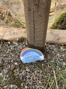 A picture of a painted rock with a rainbow on it that says: Have a Fantastic Day. 